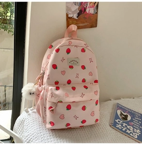 Detail of pink strawberry print backpack with plush pendant and heart patterns
