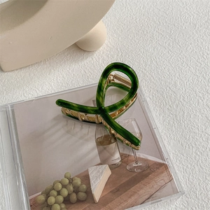 Macro shot of large dark green acetate shark hair claw with durable gold metal spring