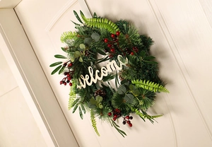 Detail of a Christmas wreath with pine needles and red berries on a wooden door