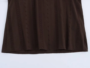 Detailed view of dark brown hem featuring vertical embroidery and hollow-out stripes