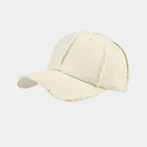 Close-up of distressed edges and stitching detail on the cream cotton baseball cap