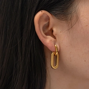 Detailed view of model wearing gold chunky twisted hoop earrings with textured finish