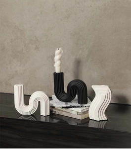 Detailed close-up of modern S-shaped ceramic candle holders with textured vertical stripes