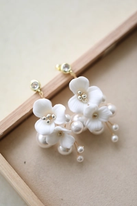 Detail of white ceramic flower hair pins with pearl accents and gold metal finish