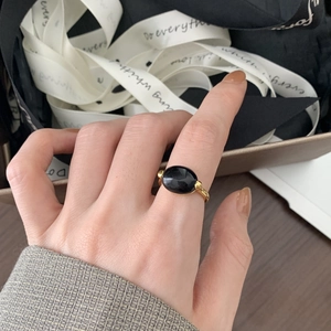 Detail of a 925 sterling silver black agate ring on finger with golden finish beads