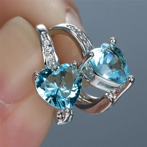 Macro detail of heart-shaped light blue gemstone earrings with sparkling cubic zirconia accents