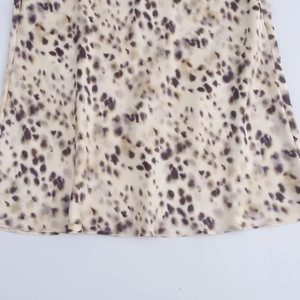 Close-up of leopard print satin midi skirt showing smooth texture and hem stitching detail