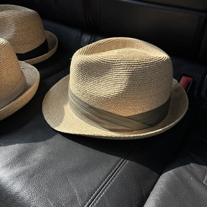 Detailed close-up of woven straw fedora hats with textured ribbons on leather seat