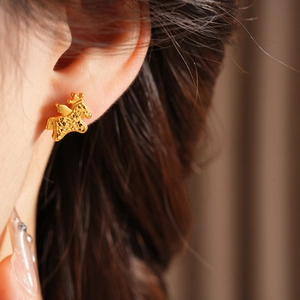 Close-up of gold-plated deer earrings featuring matte and polished finishes on model