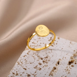 Detail of 18K gold stainless steel ring featuring sun and hand engraving on oval face