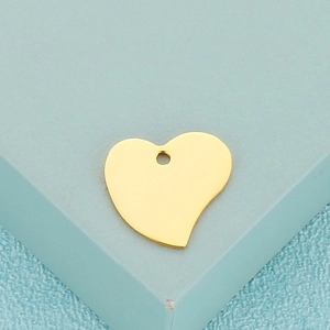 Pendentif en métal poli en forme de cœur doré sur un fond bleu-vert clair