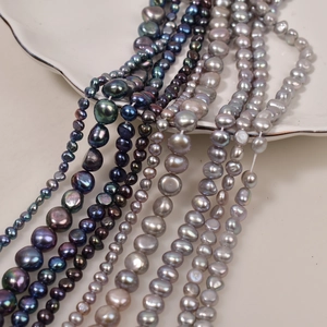Iridescent baroque pearls in peacock blue and silver grey on a white ceramic plate