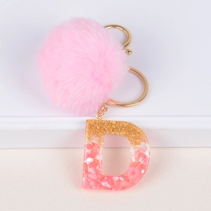 Detailed close-up of a pink faux fur pom-pom and glitter resin letter D charm keychain