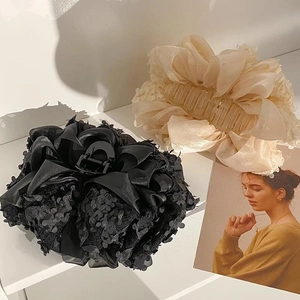 Détail de grandes barrettes à cheveux à nœud en dentelle florale et paillettes noires
