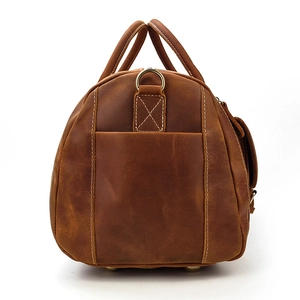 Detail of vintage brown leather travel bag showing side pocket and cross-stitch craftsmanship