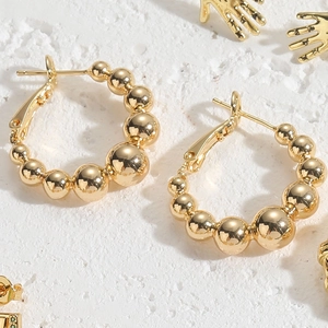 Detailed close-up of 14K gold plated beaded hoop earrings with a gradient metal design