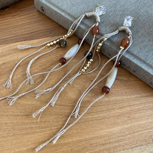 Detail shot of bohemian tassel earrings with woven ropes and beads on a wooden desk
