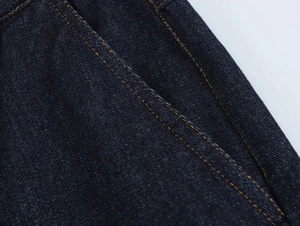 Gros plan détaillé sur le denim bleu foncé avec double couture orange renforcée