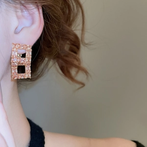 Detailed side view of a model wearing champagne gold geometric cubic zirconia earrings