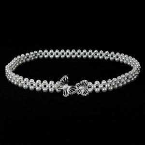 Macro detail of elastic pearl waist belt featuring a rhinestone silver bow buckle