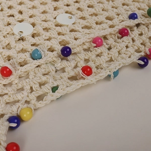 Detail of beige knit beanie featuring colorful acrylic beads and white sequins embellishment
