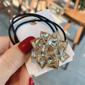 Detail of sparkling crystal sunflower hair tie with champagne gold base on elastic band