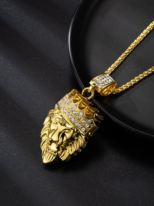 Macro shot of gold lion head pendant with rhinestone crown on black textured background