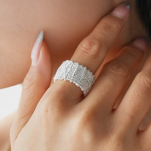 Macro detail of silver wide band ring with unique wrinkled texture and metallic finish