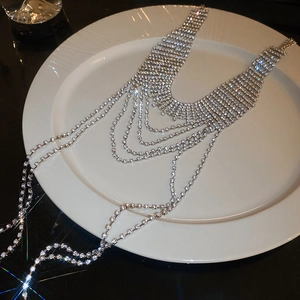 Detailed view of silver layered rhinestone tassel body chain on white ceramic plate