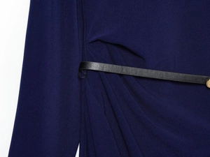 Macro detail of navy knit fabric texture featuring a black leather belt with gold buckle