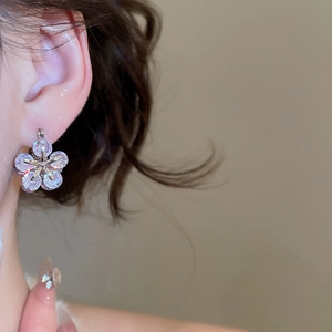 Close-up of elegant flower earrings with sparkling zircons on a silver-tone setting