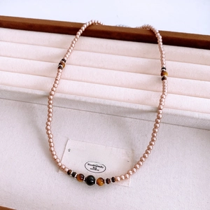 Close-up of vintage beaded necklace with tiger eye stones and pearls on a velvet tray