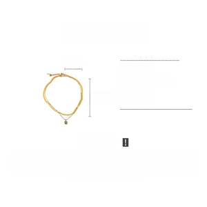Détail du collier en acier titane doré avec pendentif œil-de-chat vert et double chaîne