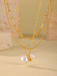 Detailed view of layered gold-plated necklaces with pearl pendants and cubic zirconia charms