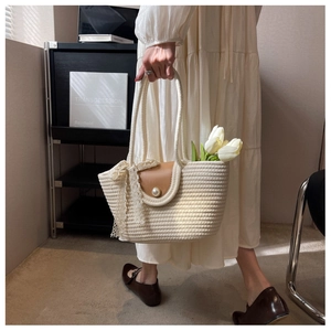 Detail of straw woven tote with brown leather buckle, pearl accents and white tulips