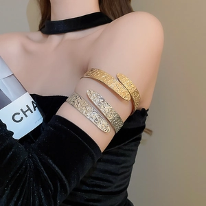 Detail of vintage metal arm cuff with intricate embossed vine patterns in gold and silver