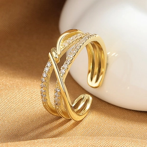 Macro shot of gold-plated layered ring with sparkling pavé crystals on silk background