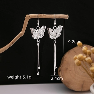 Detail of silver butterfly tassel earrings on wooden branch with product dimensions