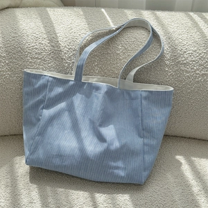 Detail der blau-weiß gestreiften Canvas-Tragetasche mit Stoffstruktur auf beigem Sofa