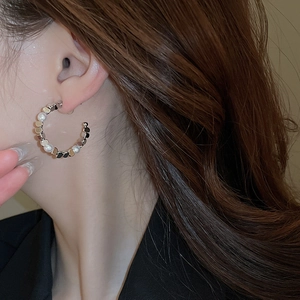 Detail view of silver hoop earrings with alternating small metal discs and pearls on model