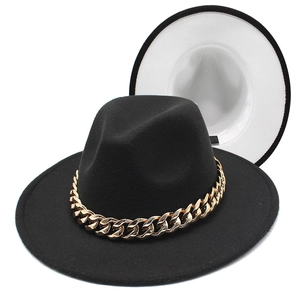 Detail of black fedora hat featuring bold gold acrylic chain and cream white inner lining