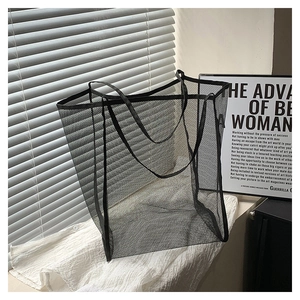 Detail of minimalist black mesh tote bag with translucent texture and light shadow effects