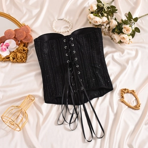 Detailed close-up of a black glitter corset top with lace-up front on satin background