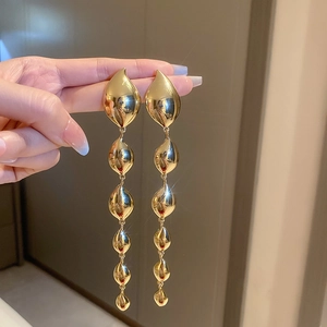 Close-up of elegant gold flower tassel earrings with teardrop metal drops held in hand