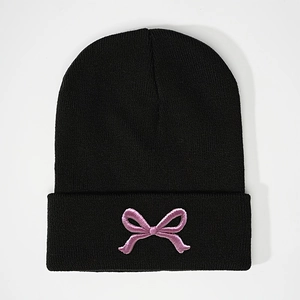 Black knit beanie hat featuring pink embroidered bow design for warm winter style