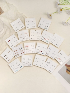 Flat lay of 15 sets of assorted minimalist alloy stud earrings on weekly gift cards