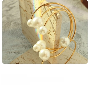 Macro detail of multi-layered 18K gold-plated geometric earrings with inlaid pearls