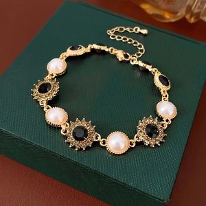 Vintage gold bracelet featuring round pearls and black sunflower crystal charms