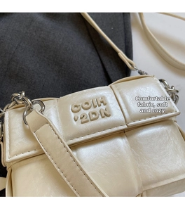 Détail de la texture tressée en cuir beige et de la bandoulière en chaîne métallique