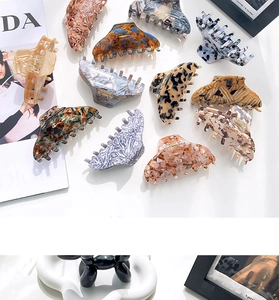 Flat lay of diverse large acetate hair claws with marble and leopard patterns on white desk